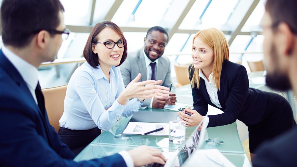 soft skills for administrative professionals 2025 report - image of woman communicating to group of colleagues around an office table