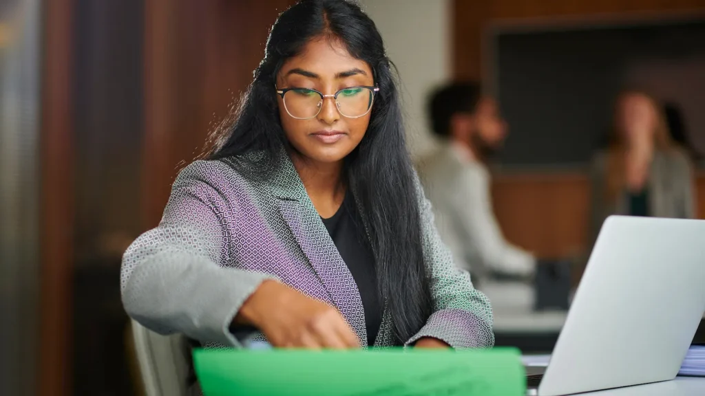 Administrative and executive assistant careers: image of young professional woman working with file folder and computer