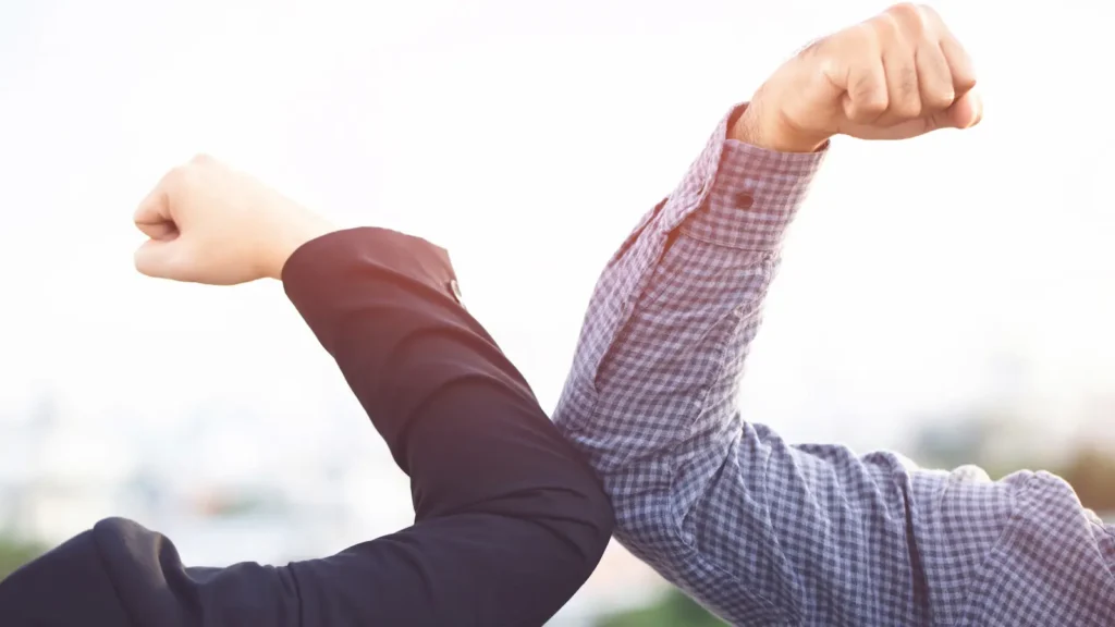 administrative assistant strategic partnership image shows the arm of a man and arm of a woman, both in business attire and held up to flex their bicep muscles, touching each other at the elbows in a show of mutual strength