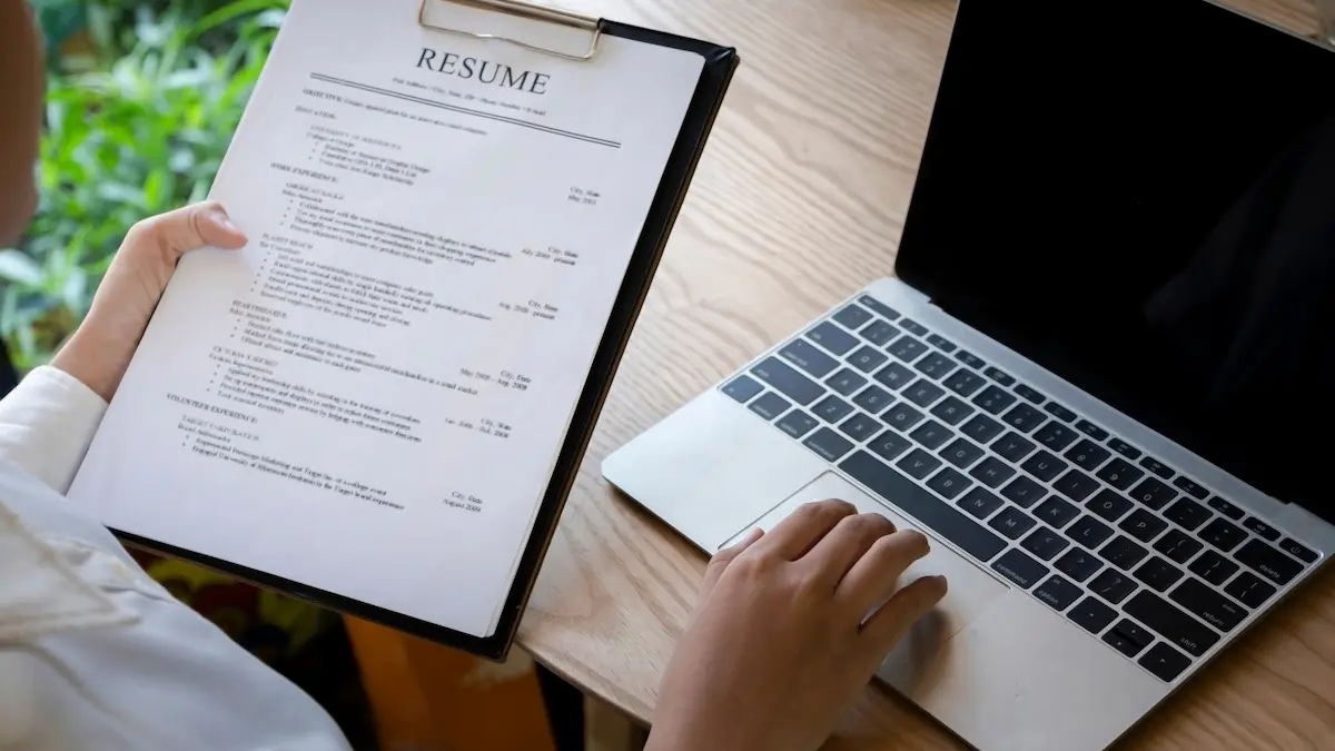 hands writing an administrative assistant cover letter at desk