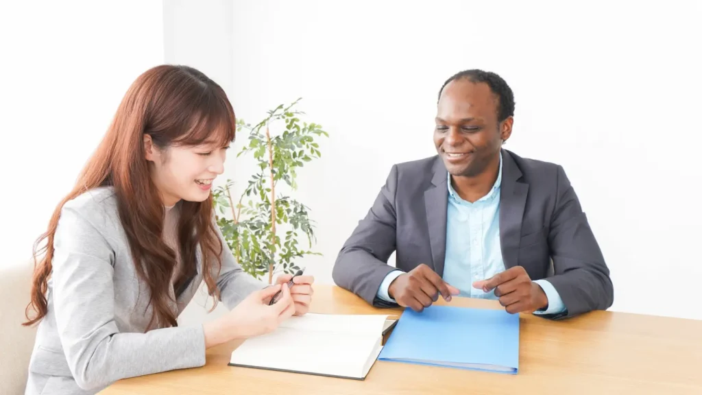Regular check-ins with your executive image shows a meeting between a woman and man in professional attire. She is presenting something to him on a notepad.