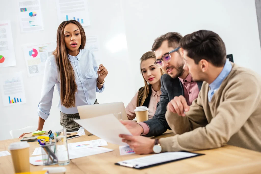 Project Management Skills for Assistants image shows a professional woman leading a meeting