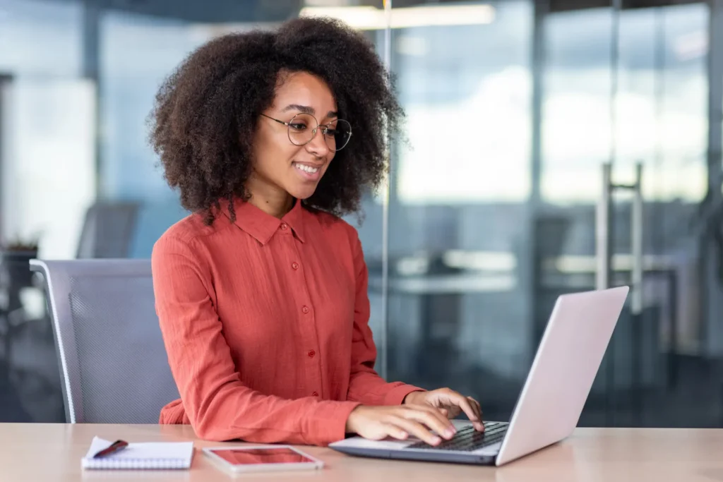 Administrative assistant working on a laptop in office.