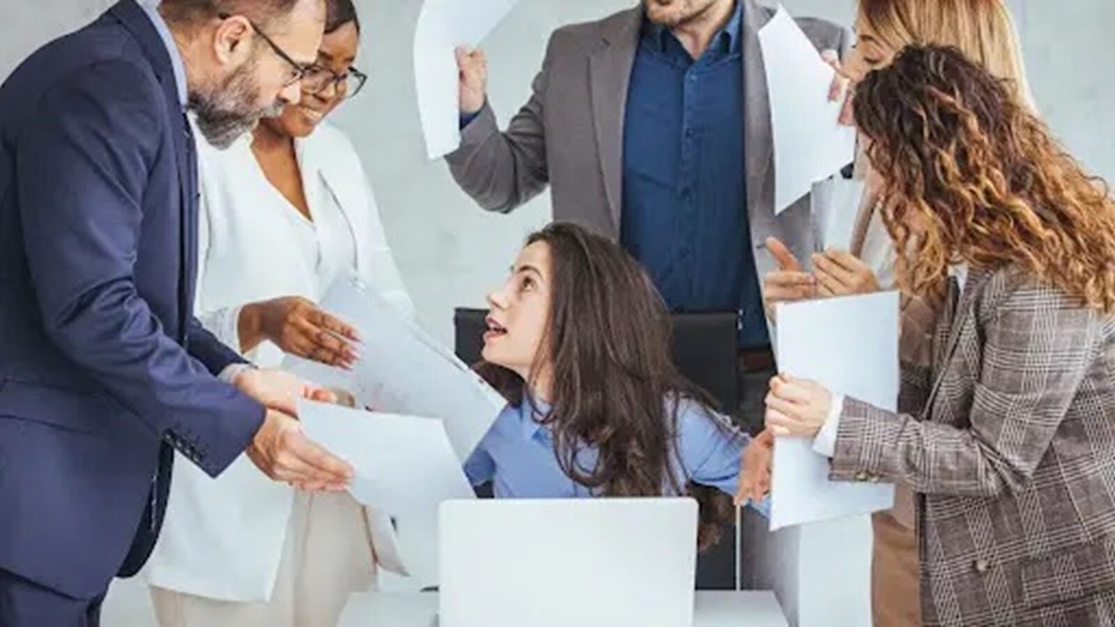 Feeling Behind at Work blog image shows harried professional woman surrounded by demanding coworkers